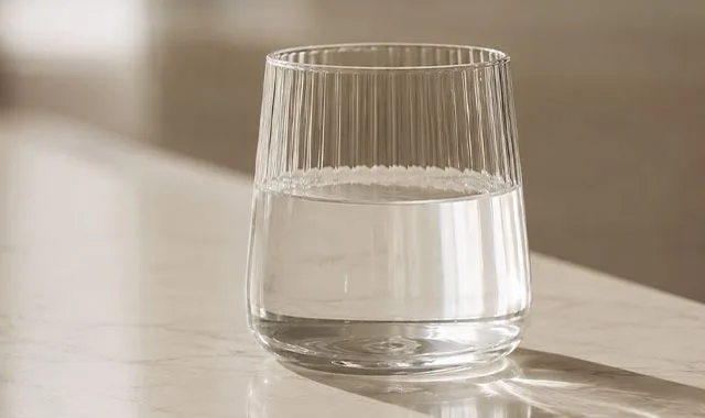 Un verre côtelé d'eau Kangen Water® claire sur un comptoir ensoleillé